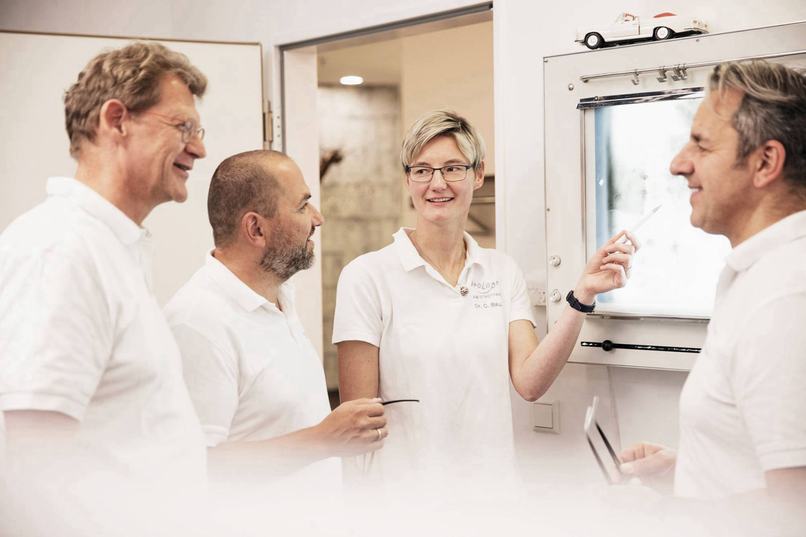 vier Ärzte im Gespräch vor einem Leuchtkasten